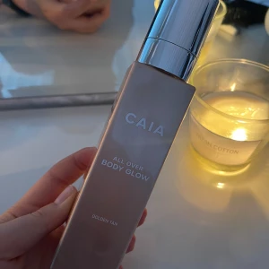 CAIA All Over Body Glow Golden Tan - Säljer en CAIA All Over Body Glow i färgen Golden Tan. Kommer i en snygg fyrkantig flaska med silvrig pump och lock. Ger huden en solkysst glow och skimrande finish, perfekt för att boosta lystern på kroppen. Enkel att applicera tack vare pumpen. Endast använd 1 pump ur. 