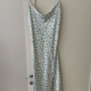 Vit blåblommig klänning med tunna axelband - Superfin medellång klänning i vitt med små blå och gröna blommor från Gina tricot. Endast använd en gång!❣️