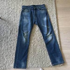 J Lindeberg jeans - Snygga blå jeans med raka ben och slitna detaljer på knäna. Klassisk femficksmodell med normal passform och coola slitningar framtill. Jeansen har en mellanblå tvätt och subtila ljusare partier för en avslappnad look.