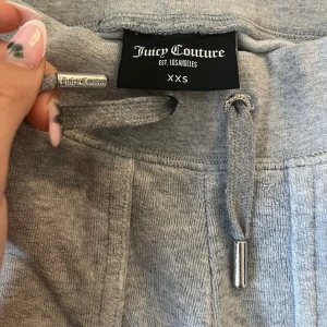 Grå mjukisbyxor Juicy Couture XXS - Grå mjukisbyxor från Juicy Couture i storlek XXS. Enda felet med dom är det slitna längst ner vid benen annars perfekta. Säljer för jag inte använder längre och har blivit små.