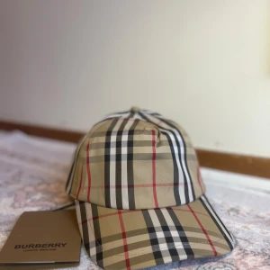Burberry Keps - 🧢 BURBERRY Keps – Ny & Stilren 🧢 🔥 Helt ny Burberry keps i den klassiska rutiga designen som aldrig går ur tiden. 👌 Perfekt för dig som vill kombinera komfort och exklusiv stil. Den är lätt, bekväm och passar lika bra till vardags som till mer uppklädda outfits. ✨ Med den ikoniska Burberry-rutan lyfter du din outfit direkt – en riktig eye-catcher! 📦 Leveranstid: 1–3 dagar, 📍 Endast kepsen ingår, 💎 Gör din look komplett med denna tidlösa designerkeps från Burberry – ett måste i garderoben!