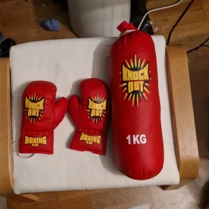 Röda boxningshandskar och boxnings boll Knock Out 8oz - Säljer ett par röda boxningshandskar från Knock Out, 8 oz, med coolt tryck i gult och svart. Perfekta för träning och boxning, tillverkade i syntetmaterial. Snygg design som sticker ut och passar dig som vill köra hårt på gymmet.