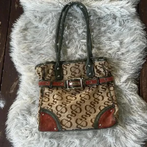 Beige och brun handväska från Sofia Coppani - Snygg handväska från Italienska märket Sofia Coppani i beige canvas med brunt S-mönster, gröna skinnhandtag och detaljer samt röda mockadetaljer. Väskan har ett bälte med spänne framtill och flera fack inuti, perfekt för att hålla ordning på dina grejer. Använd gärna köp nu❤️