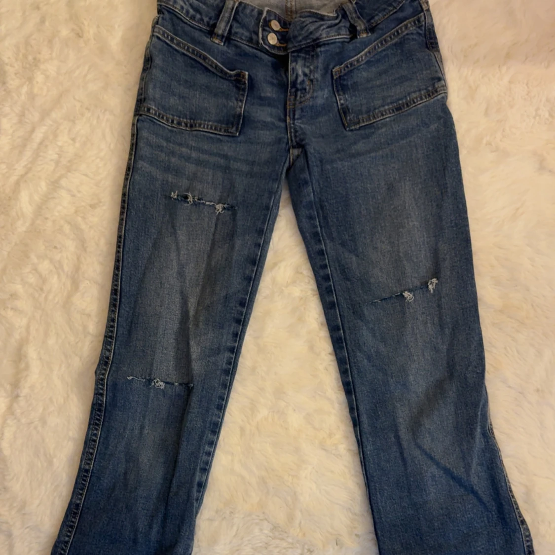 Blå jeans med slitningar och stora fickor