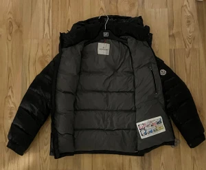 Svart Moncler pufferjacka herr -  Säljer min Moncler-dunjacka i svart. Jackan är i mycket fint skick och sparsamt använd. Varm, lätt och perfekt för vinter. Jackan är köpt på vestiaire och därför inget äktehetsbevis men nfc tagg funkar såklart som man ser på bilden