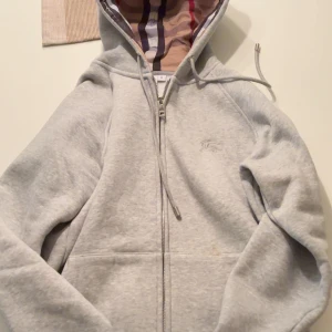 Grå hoodie från Burberry med dragkedja - Säljer en grå hoodie från Burberry med storlek M men är som S då de är små i storleken, helt ananvänd bara testad.