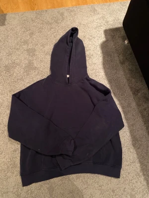 Mörkblå hoodie från Gina  - Snygg mörkblå hoodie från Gina i storlek S. Klassisk modell med huva och långärmad design, perfekt för chill dagar. Tillverkad i mjuk bomull som känns skön mot huden. Enkel och stilren utan tryck eller mönster.