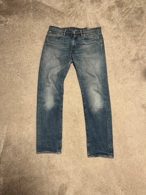Levi's 508 blå jeans straight fit - Säljer ett par Levi's 508 jeans i klassisk blå tvätt med snyggt slitna detaljer. Jeansen har rak passform, fem fickor och normal midja. Tillverkade i slitstarkt bomullsjeansmaterial och har den ikoniska Levi's-lappen bak i midjan.