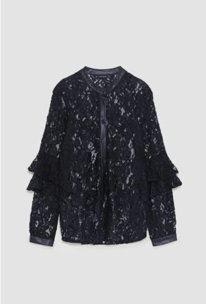 Svart spetsblus med volangärmar - Supersnygg svart blus från Zara i transparent spets med volangdetaljer på ärmarna och satinliknande kant vid hals och knäppning. 