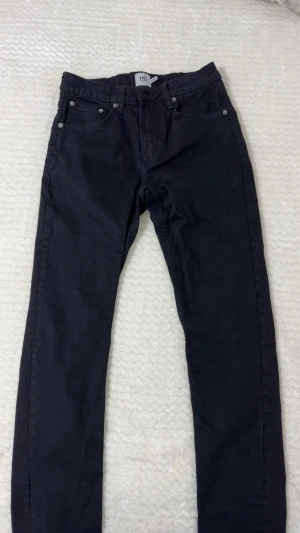 Svarta slim jeans från 157 - Svarta jeans från 157 med slim passform. Klassisk femficksmodell med bälteshällor och raka ben. Jeansen har en stilren look och är tillverkade i ett mjukt bomullsmaterial med lite stretch för extra komfort.