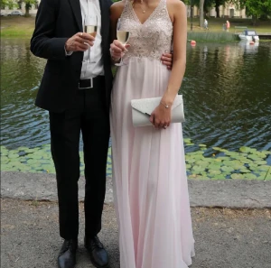 glittrig rosa balklänning  - Säljer min super fina balklänning med glittriga paljettdetaljer på överdelen och har en öppen rygg. Klänningen har en v-ringad design och korsade axelband bak. Storlek xs, den är uppsydd för mig som är 170cm + 5cm klackar, kemtvättad och ren! Köpt ny för 4200kr. kan fixa mer bilder & pris går såklart att diskutera :)) kvitto finns!! 