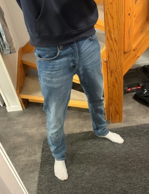 Blå Nudie Jeans Straight Fit - Säljer ett par riktigt feta blå jeans från Nudie! Perfekt för den som gillar en mer stilren look. Modellen är: 184cm 62kg och jeansen sitter bra 