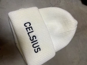 Vit stickad mössa från Celsius. Unisex  - Vit, ribbstickad mössa med bred uppvikt kant och svart broderad Celsius-logga framtill. Snygg och enkel design som passar perfekt när du vill hålla dig varm och ändå se fräsch ut. Materialet är mjukt och stretchigt för skön passform.