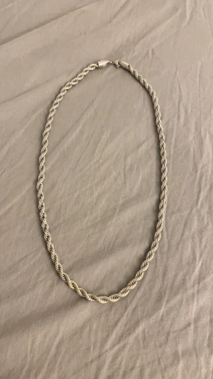 Cordell kedja från indossa - Snygg halskedja med flätad design i silverfärg. Kedjan har en klassisk look och passar perfekt för dig som vill ha en stilren accessoar. Längden är medel och kedjan har ett smidigt lås. Perfekt att bära till t-shirt eller hoodie för en cool vibe.