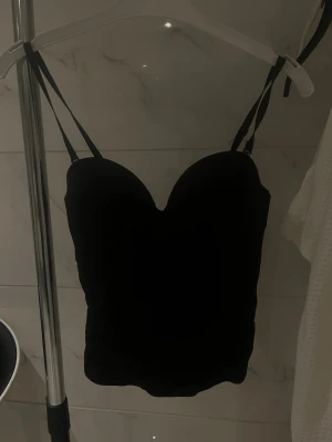 Fin korsettopp- Lindex - Jättefin svart Korsettopp med v-ringing från Lindex i storlek 75C (XS/S). Du kan justera hur tajt den skall sitta genom bh-knäppena, samt ta av bandet om du vill ha den axelbandslös. Osäker om jag vill sälja därav priset 💗Säljs inte längre på Lindex, har en likadan i vit. för mer info och bilder kom PM! 