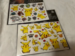 Pokemon temporära tatueringar - Flera ark med färgglada temporära tatueringar med motiv av Pikachu och andra populära Pokemon. Tatueringarna är i olika former och storlekar, med klara färger som gult, rött, blått och svart. Perfekt för att piffa upp din look med roliga och ikoniska figurer. 50kr /2st /bild  . 3 år + 