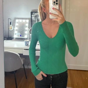 Grön ribbad långärmad tröja - Snygg grön ribbad tröja med v-ringad hals och lång ärm. Modellen är tight och sitter riktigt bra på kroppen, perfekt för dig som gillar en enkel men stilren look. Materialet är mjukt och stretchigt, vilket gör den skön att bära hela dagen.