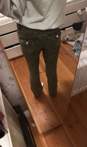 Bootcut lowwaist jeans mörkgrå - Säljer ett par snygga utsvängda och lågmidjade jeans. De har coola knappar på bakfickorna. Strl 34. Säljer pga att de inte kommer till användning längre.  Skriv om du har frågor!☺️