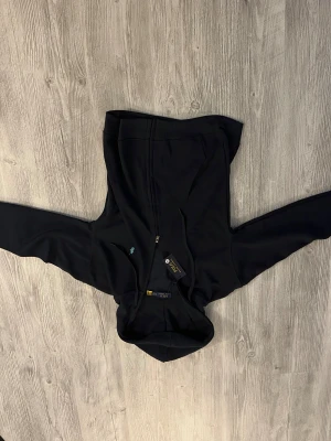 Svart hoodie från Polo Ralph Lauren - Svart hoodie från Polo Ralph Lauren med dragkedja framtill och huva med snörning. Klassisk design med långärmade ärmar och mjukt material som känns skönt mot huden. Perfekt för dig som gillar stilrena och tidlösa plagg med en sportig touch. Helt ny! 