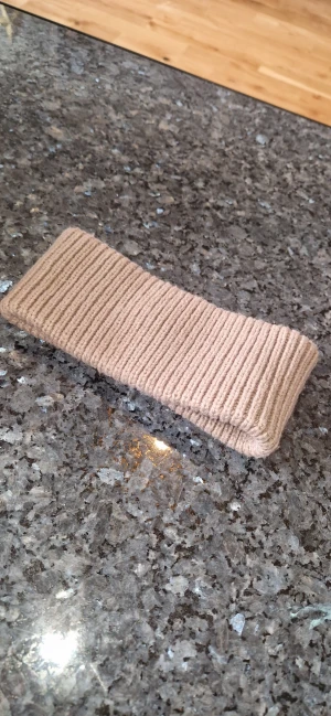 Pannband / hårband - Snyggt ribbstickat pannband i beige från 157, perfekt för dig som vill hålla öronen varma med stil. Tillverkat i 100% akryl och har en enkel, clean design som passar till allt. Mjuk och stretchig känsla, lätt att matcha med din jacka eller hoodie. Inga defekter