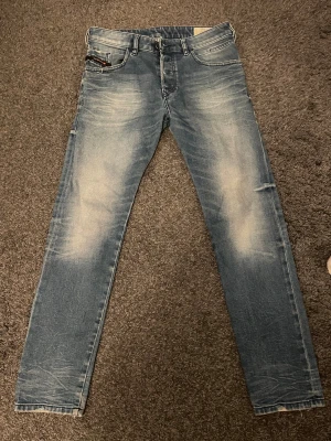 Diesel D-Bazer ljusblå tapered jeans - Säljer ett par Diesel D-Bazer jeans i ljusblå tvätt med tvärfeta slitningar. Modellen är slim/straight med klassiska fem fickor och stretchigt denimtyg för skön passform. Perfekt för dig som gillar en modern och avslappnad stil. Priset går att diskutera!
