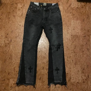 Gallery deptt jeans - Unika svarta jeans från . med broderade svarta kors på både fram- och baksida. Jeansen har råa, fransiga benslut och klassisk femficksdesign. Materialet är jeans och passformen är rak med en cool, edgy vibe. Du vet varför priset är som de är
