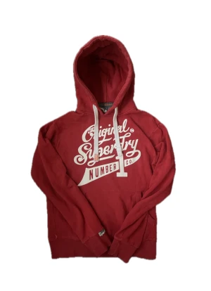 Vintage SuperDry Hoodie (Sällsynt) - Säljer nu denna sjukt snygga Superdry hoodie med ett riktigt stilrent tryck! Skicket är i princip som nytt men man får den perfekta vintage känslan! Passar fint till det mesta. Hoodien passar perfekt till höst och vinter då den är både mjuk och varm🤩 Storlek M ! Skriv vid funderingar 📲Tröjan tillverkas ej längre och därav eftertraktad!