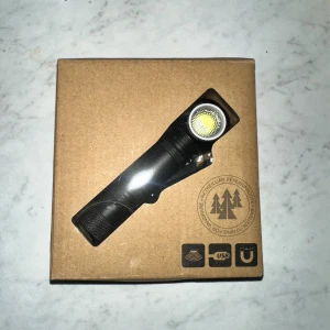 USB-laddningsbar pannlampa med magnetfäste - Kraftfull pannlampa med USB-laddning, magnetfäste och blinkande ljusfunktion. Levereras med huvudband, fäste och laddningskabel. Lampan är i nyskick och passar perfekt för friluftsliv, camping eller arbete i mörker.