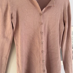 Pink dust  kofta från Saint Tropez - Snygg pink dust kofta från Saint Tropez i mjuk stickad bomull. Modellen har långa ärmar, rundad hals och knappar hela vägen framtill. Perfekt att slänga över en topp för en chill look. Enkel och stilren design som funkar till många outfits.