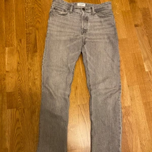 Grå jeans från Jack & Jones 28/32 - Snygga grå jeans från Jack & Jones i klassisk rak modell. Jeansen har fyra fickor, bälteshällor och stängs med dragkedja och knapp. Perfekta för dig som gillar en enkel och stilren look. Materialet är mjukt denim i bomull.