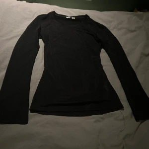 Svart långärmad topp  - Svart långärmad topp från Vintage med transparent tyg som ger en snygg shimmer-effekt. Modellen är slim och har rund halsringning. Jättesnygg att ha under en t-shirt eftersom den är genomskinlig💕