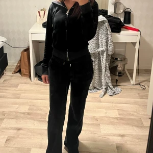 Svarta juicy couture  - Svarta juicy couture i mjuk velour. Perfekta för en chill och avslappnad stil. Snygg passform och sköna fickor framtill. Kofta i storlek XS och byxor i storlek XXS men passar XS.