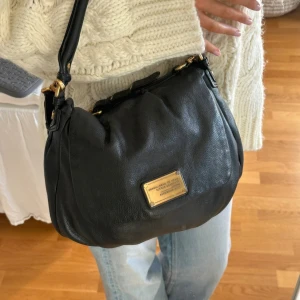 Svart Q Classic Lil Ukita väska! - Snyggaste svarta handväskan i äkta läder från Marc by Marc Jacobs. En populär och eftertraktad vintagemodell med gulddetaljer och dubbla handtag. Finns slitage som syns på bilderna, men jättefin helhet.   Det här är en tidlös modell som inte längre finns att köpa, vilket gör den extra eftertraktad. Perfekt för dig som vill ha en stilren tidlös väska med riktigt bra andrahandsvärde. Passar lika bra till vardag som till fest.  Kan hämtas hemma hos mig i Nacka eller skickas. Skriv för mer bilder 🤍