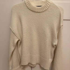 Vit stickad tröja från Gina Tricot - Supermysig vit stickad tröja från Gina Tricot i storlek XS. Tröjan har en hög, ribbad krage och breda muddar vid ärmslut och nederkant. 