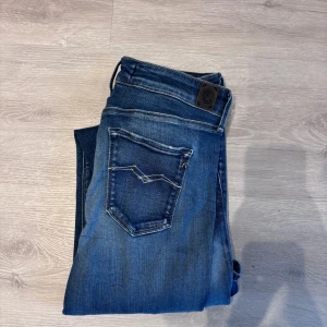 Blå Replay jeans skinny fit - Säljer ett par blå skinny jeans från Replay med klassisk femficksdesign och snygga slitningar. Jeansen har normal midja och är tillverkade i stretchigt denim för en bekväm passform. Perfekta till sneakers eller boots.