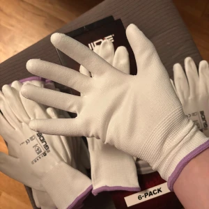 Vita arbetshandskar från Guide - Säljer ett 6-pack vita arbetshandskar från Guide. De är tunna och smidiga med lila kant vid handleden och tryckt logga på ovansidan. En låda med handskar i storlek 6. Varje förpackning innehåller 6 par handskar, totalt 20 förpackningar. Så du får 120 par handskar för det här priset. Endast en låda har packats upp för att visa vad som finns inuti.