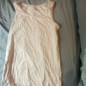 Ljusbeige linnetopp från 157 - Enkel och stilren ljusbeige linnetopp från 157. Modellen är ärmlös med klassisk rund halsringning och rak passform. Perfekt att bära till jeans eller shorts under varmare dagar. Tillverkad i mjuk bomull för en skön känsla.