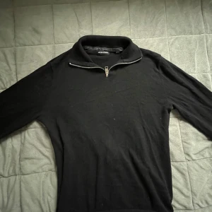 Svart half zip tröja Jack & Jones - Svart långärmad tröja från Jack & Jones med hög krage och snygg half zip-dragkedja. Tröjan är i mjukt material och har en clean, stilren look som passar perfekt till jeans eller chinos. Enkel att matcha och riktigt skön att bära. Den är storlek xs men passar perfekt till storlek S också!