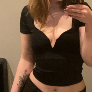 Svart croppad topp med v-ringning - Säljer en svart croppad topp med djup v-ringning och korta ärmar. Snygg och figurnära passform som framhäver midjan. Perfekt för dig som vill ha en stilren men ändå edgy look.