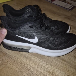Nike Air Max svart/vit sneakers 38.5 - Svarta Nike Air Max sneakers med vit sula och tydlig Air Max-dämpning. Använda 2 gånger.      Ovandelen är i mesh och syntet, med vita detaljer och snörning. Klassisk sportig look med rund tå och platt sula, perfekt för dig som gillar streetstyle och komfort.