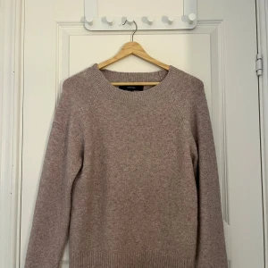 Beige stickad tröja från Weekday - Mysig beige stickad tröja från Veromoda med rund hals och långa ärmar. Tröjan har ribbade muddar vid hals, ärmslut och nederkant. Perfekt för att hålla sig varm under kyliga dagar.