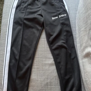 Palm Angels Track pants - Säljer dessa svarta track pants! Finns ett hål samt en liten skada därav priset. Självklart äkta (bevis sista bilden) och strl S. Fast pris, inga bud accepteras!
