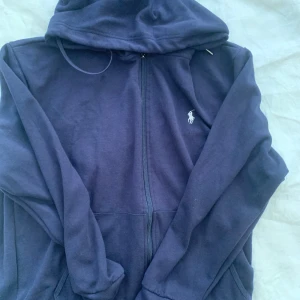 Mörkblå Tracksuit från Ralph Lauren - Säljer en full tracksuit från Ralph Lauren. De har en bekväm passform med resår och snörning i midjan. Tracksuiten är endast använd ett fåtal gånger och är i utmärkt skick. Hela sättet säljs tilsammans . 1200kr är priset för hela sättet