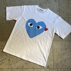 Vit Cdg Play t-shirt - Vit t-shirt från Comme des Garçons Play med stort blått hjärta och rött broderad logga på bröstet i storlek S. Nytt skick och fraktas inom 24h✅
