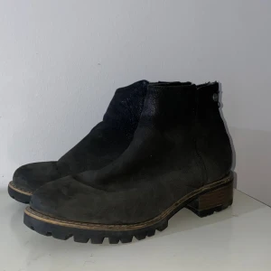 Svarta boots från Linear of Sweden - Tuffa svarta boots från Linear of Sweden med grov sula och dragkedja baktill. Skorna är i skinn och har en låg klack samt rund tå. Perfekta för dig som gillar en robust och stilren look till höst och vinter. En viktig sak med skorna är att det var svårt att öppna zippet bara så ni vet