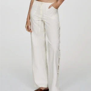 Vita linnebyxor med knyt och slits från mango - Snygga vita linnebyxor med hög midja och vida ben. Byxorna har knyt i midjan och coola slitsar längs sidorna som hålls ihop med knytband. Perfekta för en chill och trendig sommarlook.