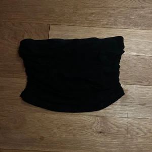 Svart och vit bandeau tubtopp - Två bandeau tubtoppar i svart och vitt, med snygg rynkad design framtill och på sidorna. Toppens form är axelbandslös och croppad. Materialet är mjukt och stretchigt,  Säljes tillsammans. Båda är i storlek S 