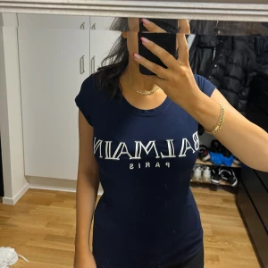 Mörkblå Balmain Paris t-shirt - Snygg mörkblå t-shirt från Balmain Paris med vit logga framtill. Modellen är figurnära med korta ärmar och rund halsringning. Perfekt för dig som gillar exklusiva och trendiga plagg med enkel design.