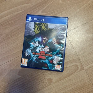 My Hero One's Justice 2 (PS4) - PS4-spelet My Hero One's Justice 2 i mycket fint skick. Komplett med fodral, skiva och manual. Inga synliga repor eller skador. Perfekt för fans av anime och fighting-spel. PEGI 12.