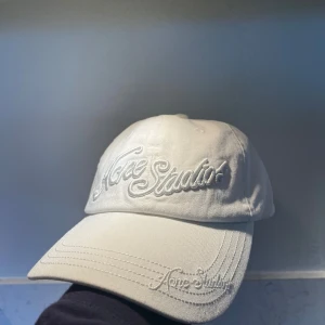 Vit keps från Acne Studios - Snygg vit keps från Acne Studios med broderad logga framtill och på skärmen. Justerbar rem baktill för perfekt passform. Tillverkad i 100% bomull för en skön och stilren look.